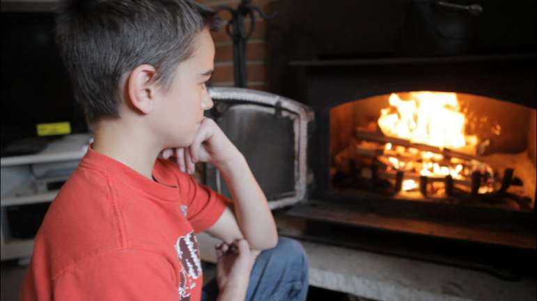 Alex Smith, 13, admires the fire he built in his family's wood stove in Puyallup.