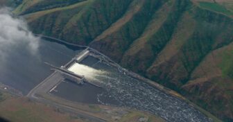 An aerial shot of a dam surrounded by hills.